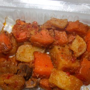 Spicy yam and plantain dish in container.
